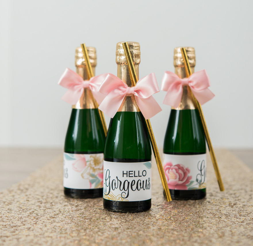 Mini Bottles of Prosecco Gift Idea with Pink Bows and Gold Straws and Personalised Hello Gorgeous Modern Floral Label on a Gold Glitter Table Runner | Confetti.co.uk